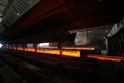 Glowing hot steel bars on the roller table of a rolling mill