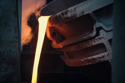 Molten iron pouring from the lip of a ladle